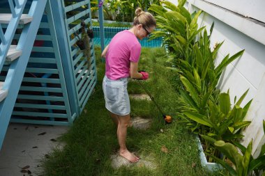 Genç bir kadın güzel bahçesini süslüyor canlı yeşilliğini ve açık hava aktivitelerine olan aşkını sergiliyor.
