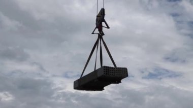 Uzun bir vinç ağır inşaat yükünü kaldırıyor..