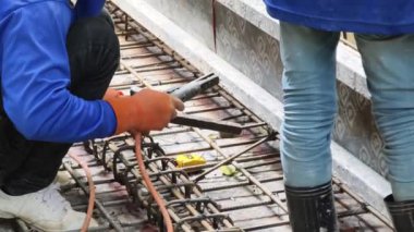 İşçiler inşaat alanındaki beton yapıların istikrarı için gerekli çelik parmaklıkları güçlendiriyorlar.
