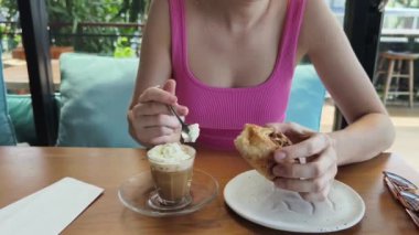 Bir kadın, modern bir kafe ortamında hoş bir yemek ve içecekten zevk alıyor.