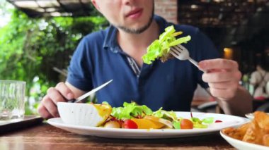 Bir adam modern bir kafe ortamında keyifli bir yemek ve içecekten zevk alıyor.