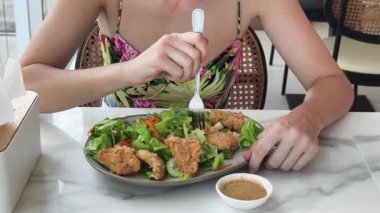 Bir kadın, modern bir kafe ortamında hoş bir yemek ve içecekten zevk alıyor.