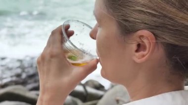 Bir kadın, doğanın sakin sükunetinde serinletici soğuk içkisinin tadını çıkarıyor.