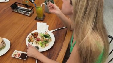 Bir kadın, modern bir kafe ortamında hoş bir yemeğin tadını çıkarıyor.