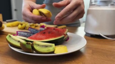 Güzel tasarlanmış modern mutfakta taze meyve kesen genç bir kadın.
