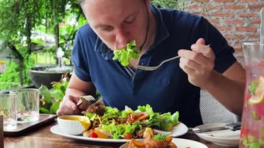 Bir adam modern bir kafe ortamında keyifli bir yemek ve içecekten zevk alıyor.