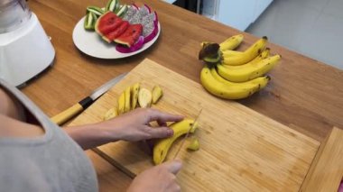 Güzel tasarlanmış modern mutfakta taze meyve kesen genç bir kadın.