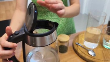 Genç bir kadın güzel tasarlanmış modern mutfakta taze kahve hazırlıyor.