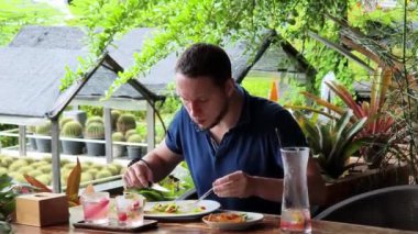 Bir adam modern bir kafe ortamında keyifli bir yemek ve içecekten zevk alıyor.