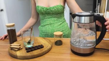 Genç bir kadın güzel tasarlanmış modern mutfakta taze kahve hazırlıyor.