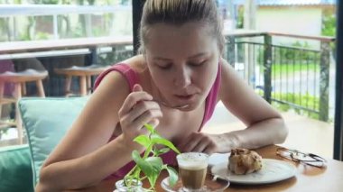 Bir kadın, modern bir kafe ortamında hoş bir yemek ve içecekten zevk alıyor.