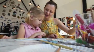 Genç bir anne ve kızı evde sanatsal bir seansın keyfini çıkarıyorlar. Renkli sanatlarıyla meşgul ve bağ kuruyorlar.