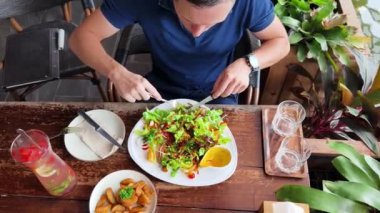 Bir adam modern bir kafe ortamında keyifli bir yemek ve içecekten zevk alıyor.