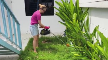 Genç bir kadın güzel bahçesini süslüyor canlı yeşilliğini ve açık hava aktivitelerine olan aşkını sergiliyor.