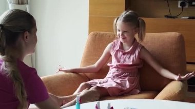 Neşeli bir anne ve kız birlikte tırnak sanatı yapıyor. 