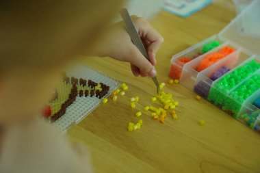 Sanat öğretmeni atölyede iki kıza termo mozaik montajı öğretiyor. 