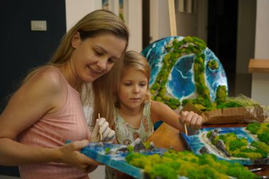 Genç bir anne ve kızı birlikte canlı doğal manzaralar yaratıyor. 