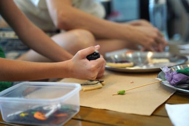 Genç anne ve kızı cadılar bayramı kurabiyelerini geniş bir modern atölyede boyuyorlar.