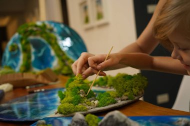 Genç bir anne ve kızı birlikte canlı doğal manzaralar yaratıyor. 