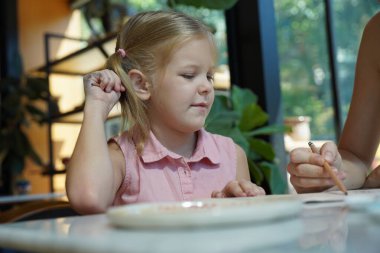 Genç bir anne ve kızı evde sanatsal bir seansın keyfini çıkarıyorlar. Renkli sanatlarıyla meşgul ve bağ kuruyorlar.