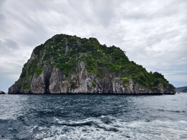 Huzurlu ve sakin bir ada manzarası kristal berrak sular ve üzerinde büyüleyici bulutlar barındırıyor.