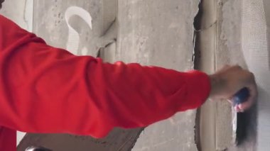 Yetenekli bir işçi titizlikle duvara çimento karışımı sürüyor. Mükemmel bir son için mala kullanıyor.