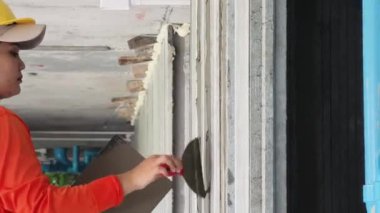 Yetenekli bir işçi titizlikle duvara çimento karışımı sürüyor. Mükemmel bir son için mala kullanıyor.