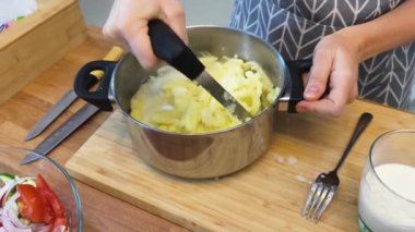 Bir kadın güzel tasarlanmış modern mutfakta ustalıkla lezzetli bir patates hazırlıyor.