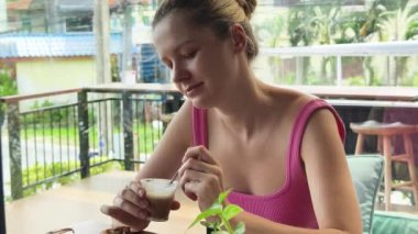 Bir kadın, modern bir kafe ortamında hoş bir yemek ve içecekten zevk alıyor.