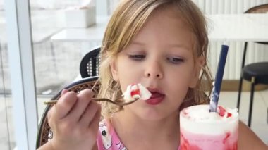 Küçük bir kız mutlu bir şekilde dondurmanın tadını çıkarıyor.