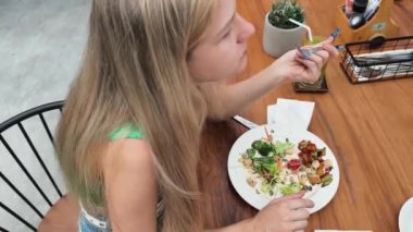 Bir kadın, modern bir kafe ortamında hoş bir yemeğin tadını çıkarıyor.