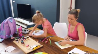 Bir anne ve küçük kızı, yaratıcılığı teşvik eden renkli bir resim faaliyetinde bulunuyorlar.