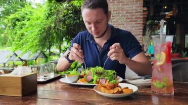 Bir adam modern bir kafe ortamında keyifli bir yemek ve içecekten zevk alıyor.