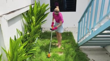 Genç bir kadın güzel bahçesini süslüyor canlı yeşilliğini ve açık hava aktivitelerine olan aşkını sergiliyor.