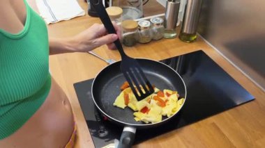 Bir kadın güzel tasarlanmış modern mutfakta ustalıkla lezzetli bir yumurta hazırlıyor.