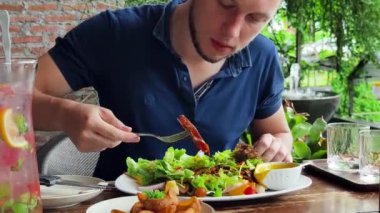 Bir adam modern bir kafe ortamında keyifli bir yemek ve içecekten zevk alıyor.