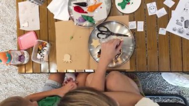 Genç anne ve kızı cadılar bayramı kurabiyelerini geniş bir modern atölyede boyuyorlar.