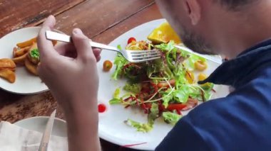 Bir adam modern bir kafe ortamında keyifli bir yemek ve içecekten zevk alıyor.