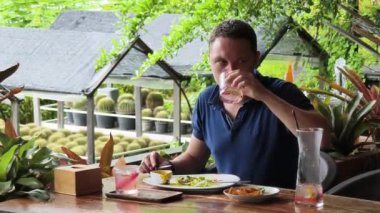 Bir adam modern bir kafe ortamında keyifli bir yemek ve içecekten zevk alıyor.