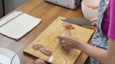 Genç bir kadın, modern mutfakta çiğ eti hamburgerlere hazırlıyor. 