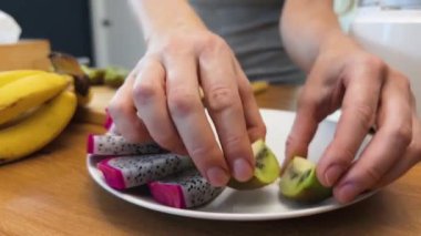 Güzel tasarlanmış modern mutfakta taze meyve kesen genç bir kadın.