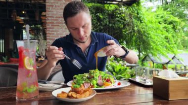 Bir adam modern bir kafe ortamında keyifli bir yemek ve içecekten zevk alıyor.