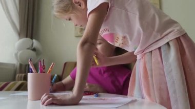 Bir anne ve kızı evde birlikte boyama faaliyetlerinde bulunuyorlar.