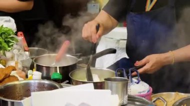 Usta bir aşçı dışarıda Tayland mutfağını tutkuyla pişiriyor.. 