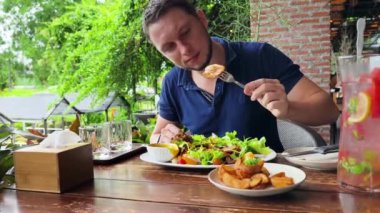 Bir adam modern bir kafe ortamında keyifli bir yemek ve içecekten zevk alıyor.