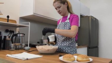 Genç bir kadın, modern mutfakta çiğ eti hamburgerlere hazırlıyor. 