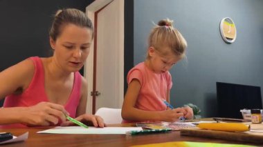 Bir anne ve küçük kızı, yaratıcılığı teşvik eden renkli bir resim faaliyetinde bulunuyorlar.