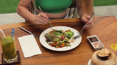 Bir kadın, modern bir kafe ortamında hoş bir yemeğin tadını çıkarıyor.