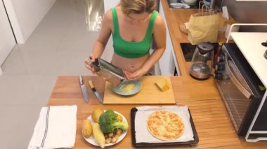 Genç bir kadın modern bir mutfakta pizza hazırlıyor..