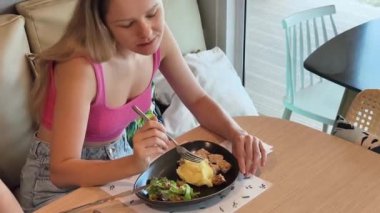 Bir kadın, modern bir kafe ortamında hoş bir yemek ve içecekten zevk alıyor.